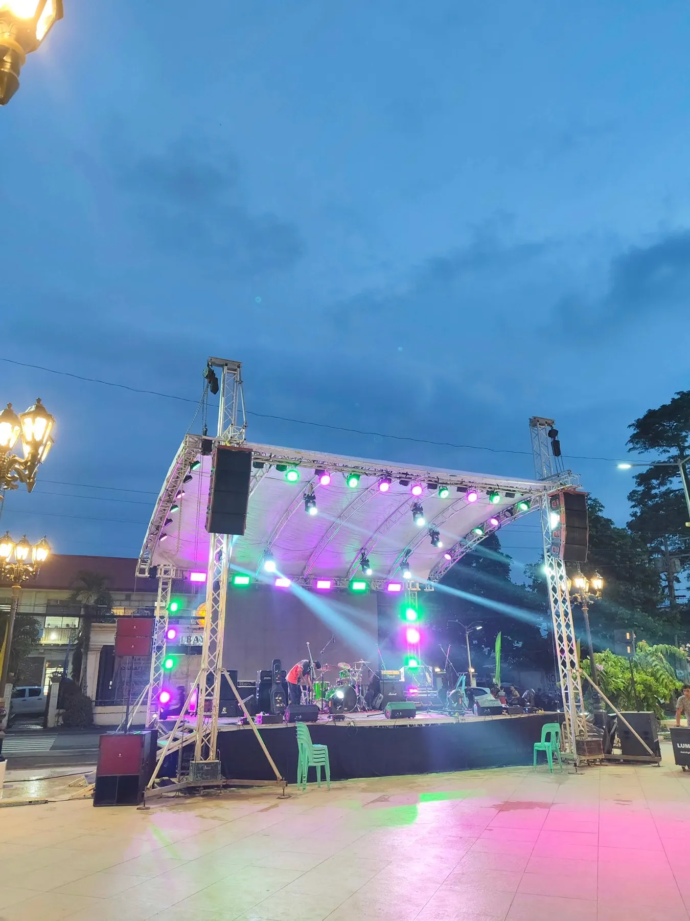 The lit stage at Julio Cardinal Rosales Plaza at dusk, before the Charter Day opening program